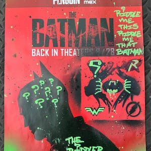 Könnte beinhalten: Ein Werbeplakat für den Film "The Batman" mit einer schwarzen Silhouette von Batman mit Fragezeichen und dem Riddler. Das Plakat ist rot und schwarz mit grünen Akzenten, einschließlich des Textes "Riddle Me This".