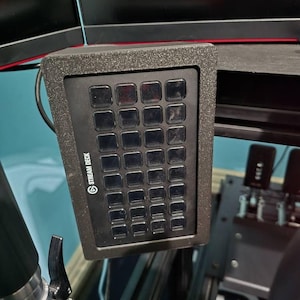 May include: A black Stream Deck with a grid of 32 customisable buttons. The Stream Deck is mounted on a black metal arm.