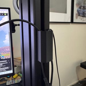 May include: A black metal vertical support structure with a ring light attached. Cables and a black box are connected to the structure. A computer monitor and other items are visible in the background.