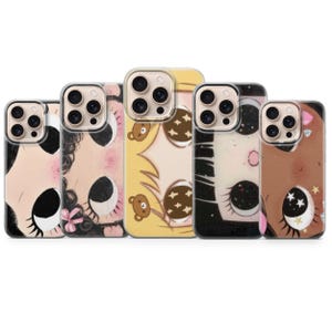 May include: Five clear phone cases featuring stylized illustrations of faces with large, expressive eyes. The designs include various hair colors, small bear motifs, and star patterns, all arranged in a row against a plain white background.
