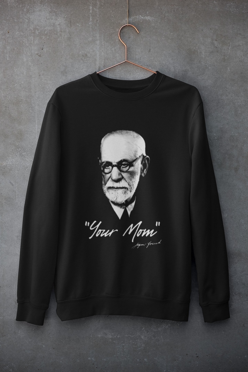 May include: Black sweatshirt featuring a black and white portrait of Sigmund Freud with the text "Your Mom" and his signature in white. The sweatshirt is hanging on a copper-colored hanger.