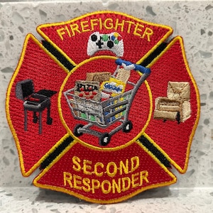 May include: Red and black firefighter patch with yellow embroidered text that reads "FIREFIGHTER SECOND RESPONDER". The patch features a shopping cart filled with groceries, a grill, and a chair.