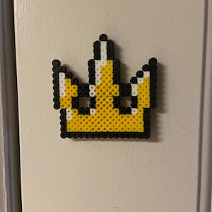 May include: A yellow and black beaded crown with white accents.