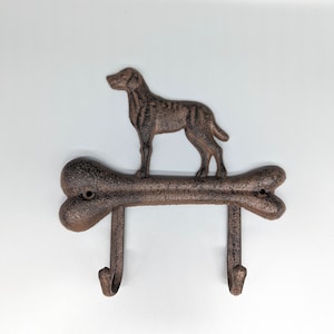 May include: A brown metal dog bone shaped hook with two hooks. A brown metal dog silhouette is on top of the bone.