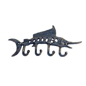 Könnte beinhalten: Ein schwarzer Wandhaken aus Gusseisen in Form eines Marlines mit vier Haken. Der Marlin befindet sich in horizontaler Position, der Schwanz links und der Kopf rechts. Die Haken befinden sich an der Unterseite des Marlines.