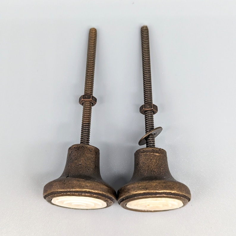 May include: Two antique-style cabinet knobs with a brass finish and a white porcelain insert. The knobs have a threaded stem and a decorative ring around the base.