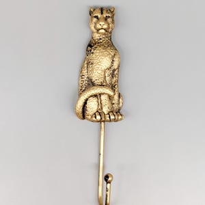 May include: Gold cheetah-shaped wall hook with a single hook extending from the bottom.