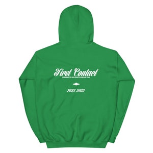 May include: Green hooded sweatshirt with white text that reads "First Contact" and "Coming to an Earth Near You" with a small UFO graphic and the dates "2023-2033".