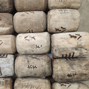 May include: A close-up of several aged wooden blocks, each bearing dark markings and characters. The blocks are rectangular with rounded edges, showing a natural wood grain. The arrangement suggests a game or decorative item, possibly of Eastern origin.