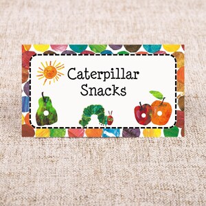 May include: A white rectangular label with a colourful border of circles. The label says "Caterpillar Snacks" and features a sun, a pear, a caterpillar, and two apples.