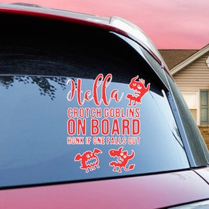 Op de afbeelding: Een rode auto met een sticker op de achterruit met de tekst "Hella Crotch Goblins On Board Honk If One Falls Out". De sticker toont twee cartoon-goblins.