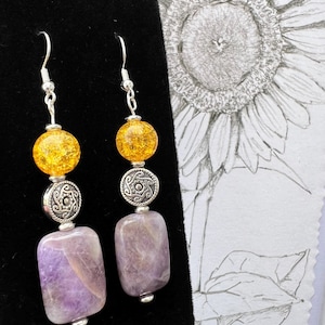 Dangle earrings with rectangular purple stone highlighted by round gold glass with sliver coated hypoallergenic hooks. Product listing 2
