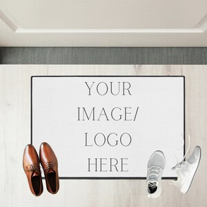 May include: White doormat with black border and text "YOUR IMAGE/LOGO HERE" on a light wood floor. Two pairs of shoes are on the floor, one pair is brown leather and the other is white athletic shoes.