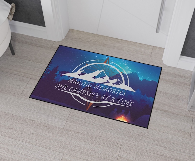 May include: A blue doormat with a compass design and the text "Making Memories One Campsite at a Time Est. 2022". The background is a starry night sky with mountains and trees.