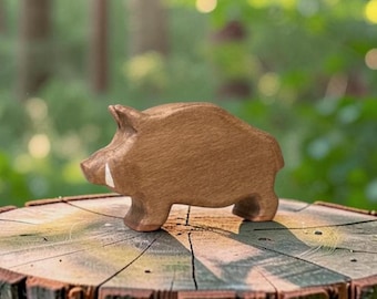May include: A brown wooden figurine of a wild boar with a smooth, polished finish and a single white painted tusk on its snout. The animal is depicted in a standing profile position, showcasing the natural wood grain texture throughout its body.