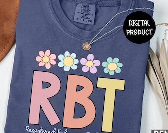 May include: A navy blue t-shirt with the text "RBT" in pink and yellow, and the words "Registered Behavior Technician" below. Above the letters are pastel-colored flowers. The shirt has a Comfort Colors tag and a silver necklace.
