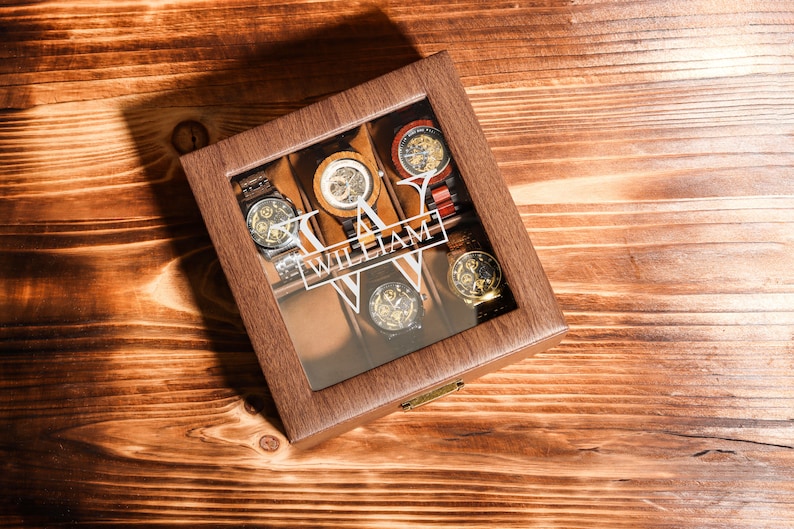 May include: A wooden watch box with a glass top. The box has a brown finish and is personalised with the name "William". The box is filled with six watches.