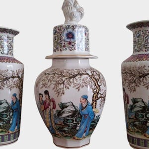 May include: Three white porcelain vases with intricate floral and landscape designs. The center vase has a lid with a rooster finial. All three vases feature painted figures in traditional Chinese clothing.
