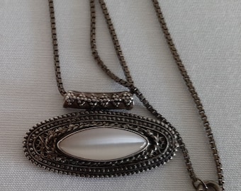 May include: A silver chain necklace with a silver oval pendant featuring a white iridescent stone.