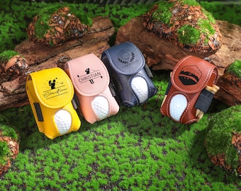 May include: Four personalized golf ball holders in different colors: yellow, pink, blue, and brown. Each holder has a different design and name, including "Christian" and "Andreas".