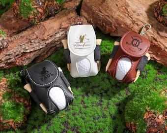 May include: Three personalized golf ball holders. One is white with a golfer graphic and the name "Christian" on it. Another is black with the name "Paul" on it. The third is brown with a golf club and the name "Christian Dennis" on it.