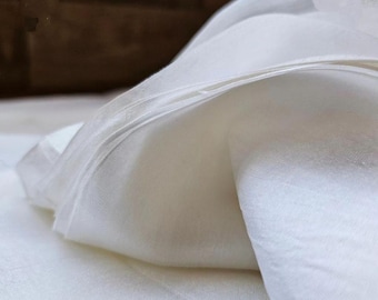 May include: White sheer fabric with a smooth, silky texture. The fabric is folded in a way that shows its drape and flow.