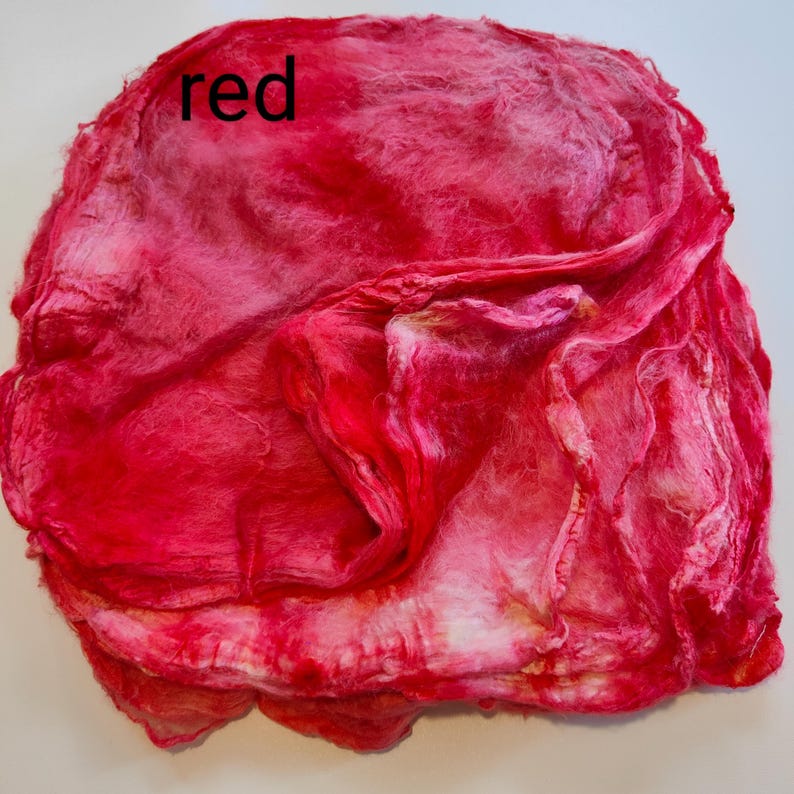 May include: A red and white silk fabric with a soft, textured surface. The fabric is folded and crumpled, creating a dynamic and abstract design.