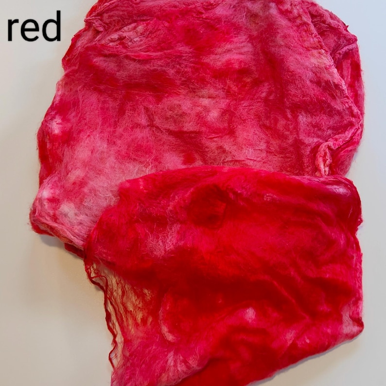 May include: Red fabric with a tie-dye pattern. The fabric is soft and has a fuzzy texture.