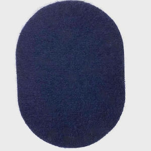 May include: A navy blue, oval rug with a textured, plush surface. The rug has rounded edges and a solid colour, suitable for various interior design styles. The rug is made of a soft material.