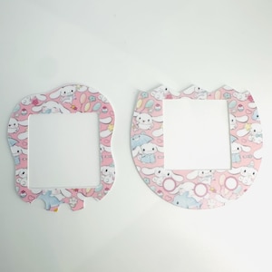 May include: Two pink and white light switch covers with a cartoon bunny pattern. The covers are shaped like a rounded rectangle and an oval.