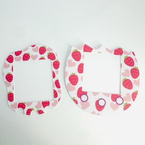 Può includere: Due placche per interruttori di luce bianche con un motivo a fragole e cuori rosa. Le placche hanno la forma di un rettangolo arrotondato e di un cerchio.