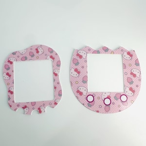 Pode incluir: Duas folhas de adesivos com tema Hello Kitty rosa e branco para um Tamagotchi.