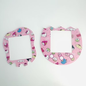 Op de afbeelding: Twee roze lichtschakelaars met een wit vierkant in het midden. Beide schakelaars hebben een patroon van Hello Kitty-personages, donuts en sprinkels.