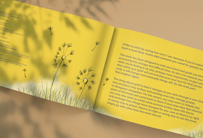 May include: Open book with yellow pages and text about grief. The book has dandelion illustrations on the cover and inside pages.
