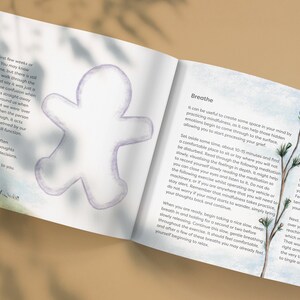 May include: An open book with a light blue background and illustrations of a gingerbread man and a small dog. The text on the page reads "Breathe" and "It can be useful to create some space in your mind by practicing mindfulness, as it can help those hidden emotions begin to come through to the surface, allowing you to start processing your grief."