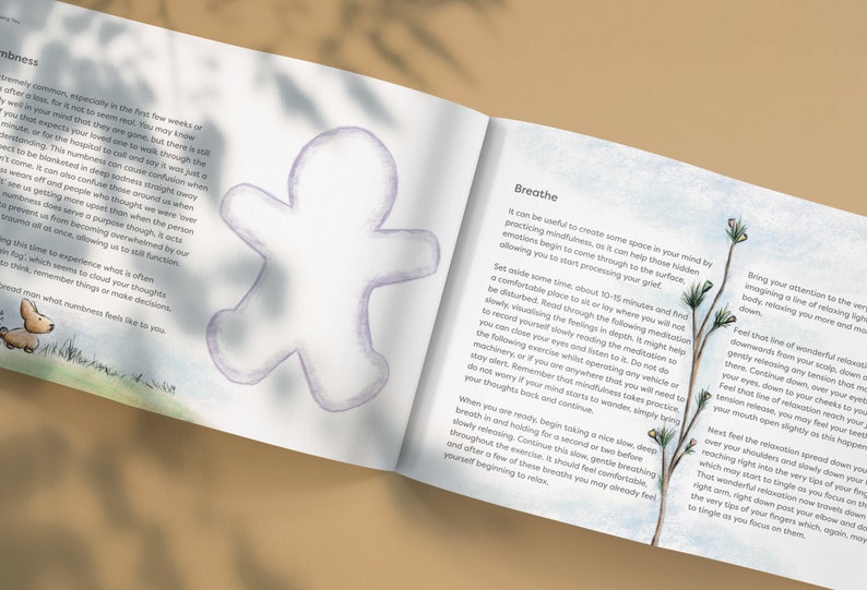 May include: An open book with a light blue background and illustrations of a gingerbread man and a small dog. The text on the page reads "Breathe" and "It can be useful to create some space in your mind by practicing mindfulness, as it can help those hidden emotions begin to come through to the surface, allowing you to start processing your grief."