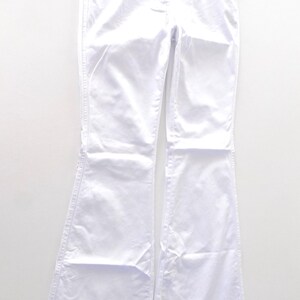 Puede incluir: Pantalones vaqueros blancos de pierna ancha con un ajuste recto desde la cintura hasta la rodilla y una abertura de pierna acampanada.