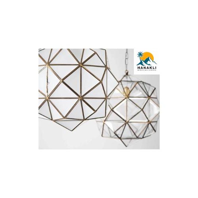 May include: Two geometric glass pendant lights with a brass frame. The lights are hanging from a chain.