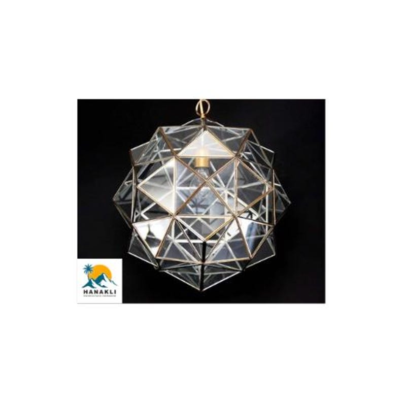 May include: A geometric glass and brass pendant light fixture with a clear glass shade. The shade is made up of many small triangles that create a unique and modern design.