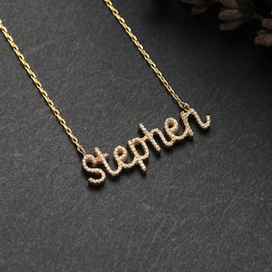 May include: A gold necklace with a cursive name pendant that says "Stephen" in sparkling diamonds.