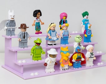 May include: A purple three-tiered display stand with 13 different Lego minifigures. The minifigures include Batman, Kermit the Frog, Alice in Wonderland, a scientist, a wrestler, and more.