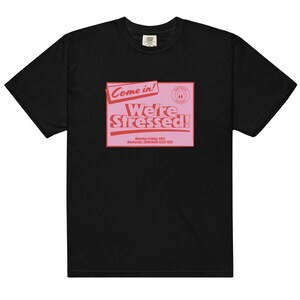 K&ouml;nnte beinhalten: Schwarzes T-Shirt mit einer pinkfarbenen Grafik, auf der "Come in! We're Stressed!" steht, darunter der Text "Monday-Friday: YES! Weekends: SOMEHOW ALSO YES!"