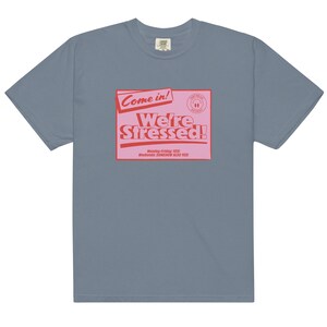 K&ouml;nnte beinhalten: Ein hellblaues T-Shirt mit einer pinkfarbenen und roten Grafik, auf der "Come in! We're Stressed!" steht, darunter der Text "Monday-Friday: YES! Weekends: SOMEHOW ALSO YES!"