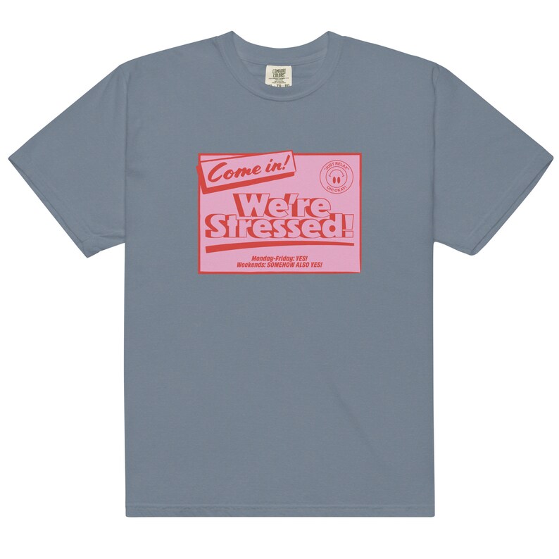 K&ouml;nnte beinhalten: Ein hellblaues T-Shirt mit einer pinkfarbenen und roten Grafik, auf der "Come in! We're Stressed!" steht, darunter der Text "Monday-Friday: YES! Weekends: SOMEHOW ALSO YES!"