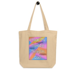 Könnte beinhalten: Eine beige Tragetasche mit einer bunten Grafik, auf der "Ich hoffe, mein Therapeut findet mich cool!" steht. Die Grafik hat ein Farbschema in Pink, Blau, Gelb und Orange.