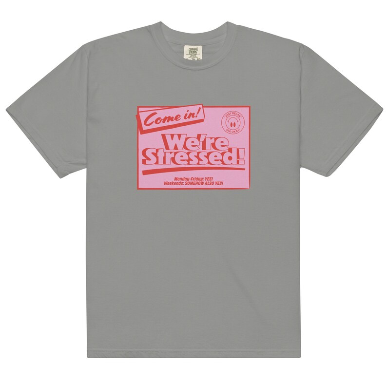 K&ouml;nnte beinhalten: Ein graues T-Shirt mit einer pinkfarbenen und roten Grafik, auf der "Come in! We're Stressed!" steht, darunter der Text "Monday-Friday: YES! Weekends: SOMEHOW ALSO YES!"