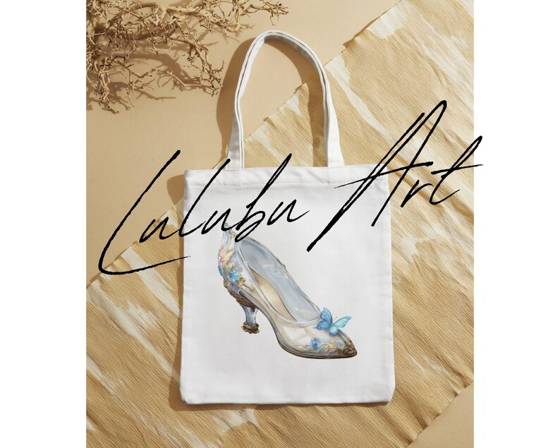 May include: White tote bag featuring a watercolor illustration of a glass slipper with blue butterfly accents. The bag has the text "Lalabu Art" in a handwritten font.