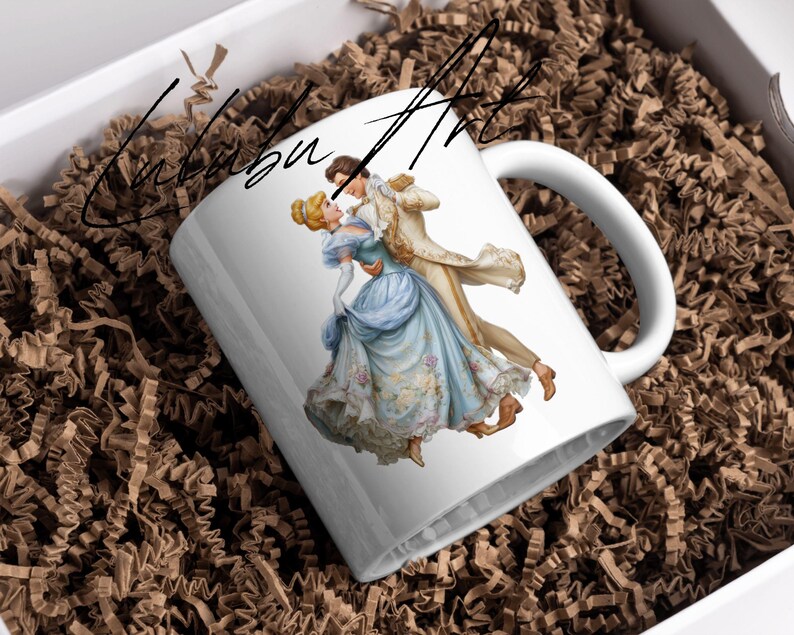 May include: White ceramic mug featuring a romantic illustration of a couple dancing in formal attire. The woman wears a blue gown, and the man is in a gold coat. The mug is inside a white box with brown paper filler. The text "Calubu Art" is written on the mug.