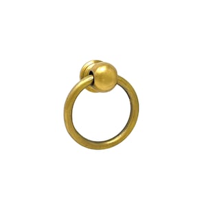May include: A gold-toned ring pull handle with a round knob. The handle is made of metal and has a smooth finish.