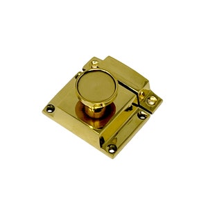 May include: A polished brass cabinet latch with a round knob. The latch has a square base and a rectangular strike plate.